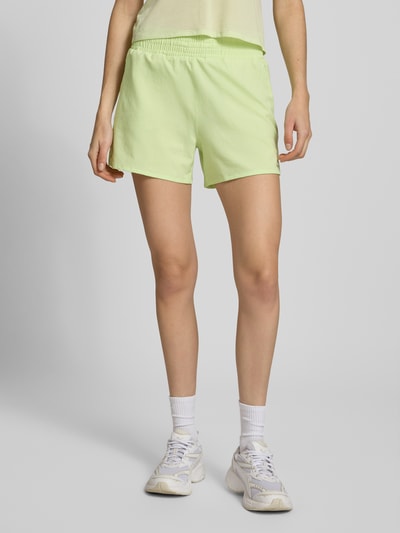 Frauenmodel trägt Regular Fit Shorts mit elastischem Bund Modell 'Kout' von Salomon in hellem Grün, glatte Textur, integrierter Slip, Ganzkörperansicht von vorne.
