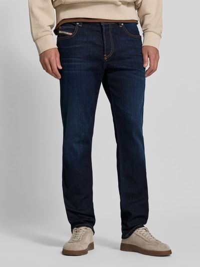 Männermodel trägt Straight Fit Jeans aus Viskose-Mix von Diesel in Dunkelblau mit 5-Pocket-Design und Logo-Detail, Nahaufnahme Oberkörper. Elastischer Stoff, Knopf- und Reißverschluss, Bundweite 43 cm, Innenbeinlänge 83 cm.