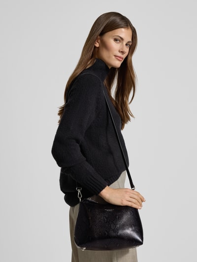 Frauenmodel trägt Crossbody Bag mit Label-Detail Modell 'LILLEBY' von Seidenfelt, schwarze strukturierte Oberfläche, abnehmbarer Schulterriemen, Hauptfach mit Reißverschluss, Innenfach mit Reißverschluss, Maße 25x19x10 cm, Länge Schulterriemen 107 cm, Nahaufnahme Oberkörper.