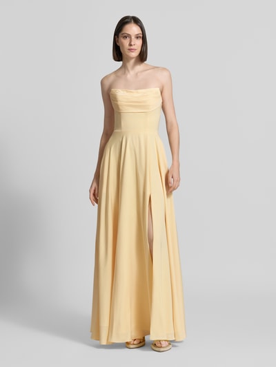 Frauenmodel trägt Maxikleid im Off-Shoulder-Look von Luxuar in hellem Gelb, taillierter Schnitt, Gehschlitz, Rückseitige Schnürung, Ganzkörperansicht von vorne. Rückenlänge bei Größe 36: 134 cm, Brustweite bei Größe 36: 43 cm.