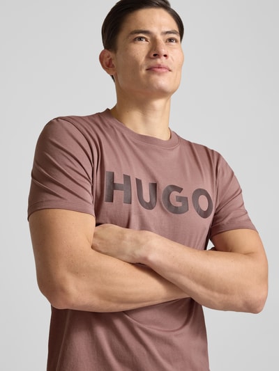 Männermodel trägt Regular Fit T-Shirt aus reiner Baumwolle Modell 'DULIVIO' von HUGO in Optik: Unifarben, Label-Print, Rundhals, Kurzarm, Nahaufnahme Oberkörper.