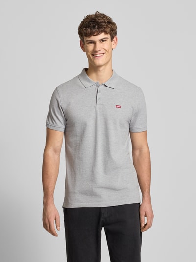 Męski model nosi Poloshirt mit Label-Detail od Levi's®, szare, bawełna, regular fit, krótka listwa guzikowa, widok z przodu, ujęcie całej sylwetki.