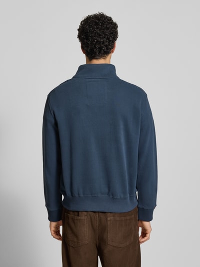 Männermodel trägt Regular Fit Sweatshirt mit Logo-Stitching von Superdry aus Baumwoll-Mix in Dunkelblau, Rückenlänge 65 cm, Ganzkörperansicht Rückansicht.