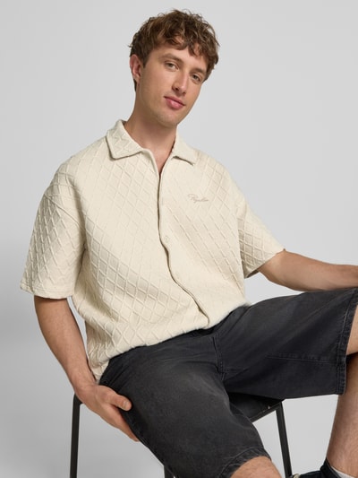 Männermodel trägt Modern Fit Freizeithemd mit Logo-Stitching Modell 'Jovren' von Pegador, Strukturmuster, helle Farbe, Nahaufnahme Oberkörper.