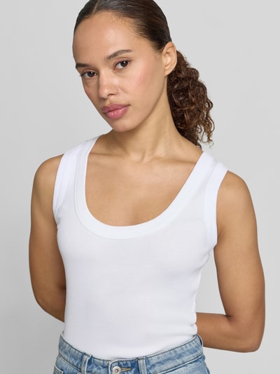 Frauenmodel trägt weißes Tanktop mit Rundhalsausschnitt Modell 'TAVIRA' von Drykorn aus Reine Baumwolle, Körpernahe Passform, Feinripp, Nahaufnahme Oberkörper.