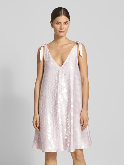 Frauenmodel trägt Relaxed Fit Kleid mit Allover-Paillettenbesatz von Jake*s Cocktail in Rosa mit V-Ausschnitt und Zierschleifen, Ganzkörperansicht von vorne.