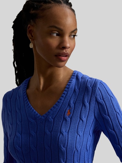 Vrouwenmodel draagt 'Regular Fit Strickpullover aus Woll-Kaschmir-Mix' van Polo Ralph Lauren, blauw, kabelpatroon, logo, close-up borst.