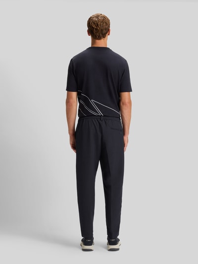 Männermodel trägt Tapered Bundfaltenhose mit halbelastischer Bund Modell 'CONVERT-PLEAT' van BOSS Green, unifarben, 4-way stretch, ganzlich van achteren.