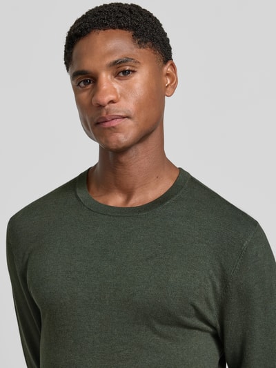 Männermodel trägt Strickpullover mit geripptem Rundhalsausschnitt von MCNEAL in Dunkelgrün, taillierte Passform, Nahaufnahme Oberkörper.