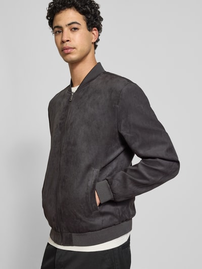 Męski model nosi Regular Fit Blouson in Lederoptik Model 'LUCAS' von Only & Sons, efekt: jednolity kolor, krój regular fit, kołnierz college, zamek błyskawiczny, pas na plecach, długi rękaw, prążkowane wykończenie, wpuszczane kieszenie boczne, kieszeń wewnętrzna, wykończenie materiału: sztuczna skóra; całopostaciowy widok z przodu