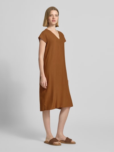Frauenmodel trägt knielanges Leinenkleid mit V-Ausschnitt Modell 'Ina' von Soyaconcept im Leinen-Mix mit Viskose-Anteil, Loose-Fit, seitliche Schlitze, einfarbig in Braun, weiche Textur, Knielänge, Ganzkörperansicht von vorne.