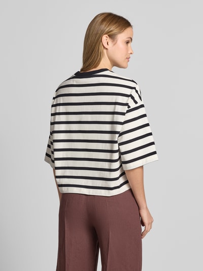Männermodel trägt Cropped T-Shirt mit Motiv-Stitching von Smith and Soul, bawełna, krój loose fit, krój krótki, okrągły dekolt, długość tyłu 52 cm w rozmiarze S, biało-czarne pasy, gładka faktura, Ganzkörperansicht Rückansicht.