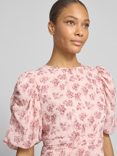 Kobieta modelka nosi długą sukienkę z szyfonu z bufiaste rękawy i okrągły dekolt, wzór na całej powierzchni, Maxikleid aus Chiffon mit Puffärmeln Modell 'A-Linie' od Neo Noir, model 'Kikka', Szerokość w rozmiarze 36: 43 cm, długość tyłu 138 cm, długość rękawów 35 cm, półzbliżenie górnej części ciała.