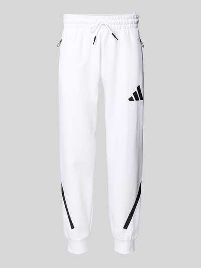 Produktfoto, Sweatpants mit elastischem Bund von adidas Sportswear in Weiß mit schwarzen Details, Baumwolle, lockerer Schnitt, Reißverschlusstaschen
