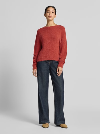 Frauenmodel trägt Strickpullover aus Alpaka-Mix Modell 'GIUNCO' von Marella in Rot, kombiniert mit blauen Jeans; Ganzkörperansicht von vorne. Damen Strickpullover, Regular Fit, Rundhalsausschnitt, Woll-Anteil, Rückenlänge 50 cm, Ärmellänge 69 cm.