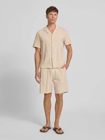 Męski model nosi Resort Fit Freizeithemd aus reiner Baumwolle od s.Oliver RED LABEL, jasnobeżowa koszula casualowa, luźny materiał, gładka tekstura, całkowity widok z przodu.