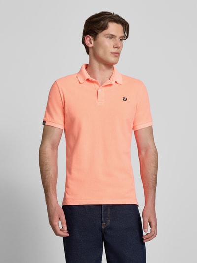 Męski model nosi Regular Fit Poloshirt mit Logo-Stitching od Superdry, bawełna, krój regular fit, logo, kołnierzyk polo, krótki rękaw, długość tyłu w rozmiarze M: 67 cm. Ganzkörperansicht von vorne