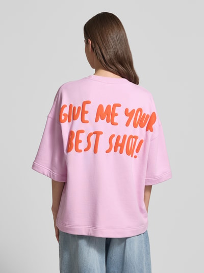 Frauenmodel trägt Loose Fit Sweatshirt mit Snoopy®-Print Modell 'JUMPI EMBO' von Essentiel Antwerp in Rosa, Motiv-Print in Orange, Rundhals, 3/4-Arm, Baumwoll-Mix, ganzkörperansicht rückansicht.