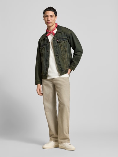 Männermodel trägt Relaxed Fit Jeansjacke aus reiner Baumwolle Modell 'TRUCKER' von Levi's® im Used Look, Ganzkörperansicht von vorne.