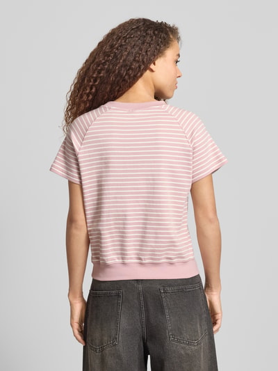 Modelka nosi Relaxed Fit T-Shirt aus Baumwoll-Mix mit Label-Patch od G-Star Raw, różowe paski, bawełna z elastanem, krótki rękaw, luźny krój, okrągły dekolt, elastyczny dół, długość tyłu 57 cm w rozmiarze S, widok całej sylwetki z tyłu.