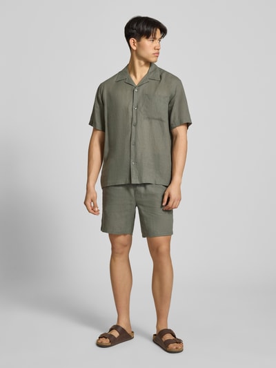Męski model nosi Regular Fit Shorts aus Leinen-Viskose-Mix Modell 'LAURENCE' von Only & Sons, jednolity kolor, elastyczny pas, kieszenie boczne i tylne, krój regular fit, materiał mieszanka lnu i wiskozy, zdjęcie całej sylwetki z przodu.