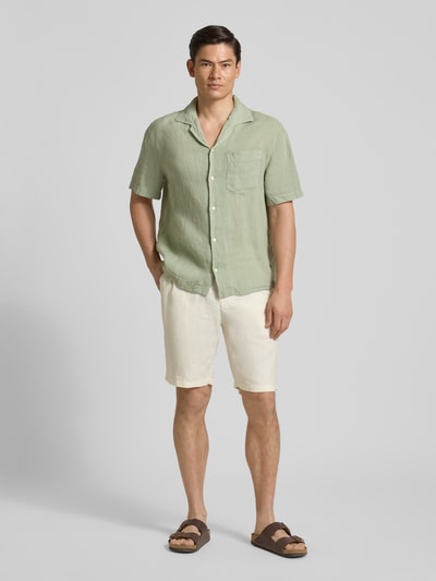 Männermodel trägt Regular Fit Freizeithemd aus reinem Leinen Modell 'EXOLINO' von HUGO in hellem Grün, unifarben, mit Bowling-Kragen, Kurzarm und Brusttasche, Ganzkörperansicht von vorne.