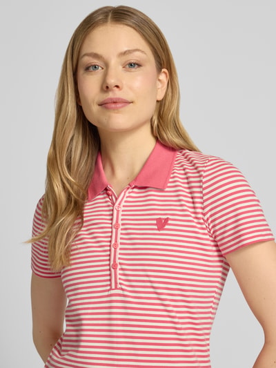 Frauenmodel trägt Regular Fit Poloshirt aus Baumwoll-Mix von Tom Tailor, Optik:Allover-Muster, Muster: gestreift, Motiv-Stitching, Polokragen, V-Ausschnitt, Verschluss: kurze Knopfleiste, Ärmelform: Kurzarm, Materialverarbeitung: Piqué, Material: Baumwoll-Mix, Farbtöne in Rosa und Weiß, Nahaufnahme Oberkörper.