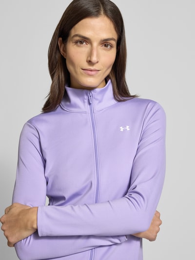 Frauenmodel trägt Motion Jacket mit Logo-Print Modell 'EMEA' von Under Armour in Flieder, körpernaher Schnitt, Stehkragen, Nahaufnahme Oberkörper.