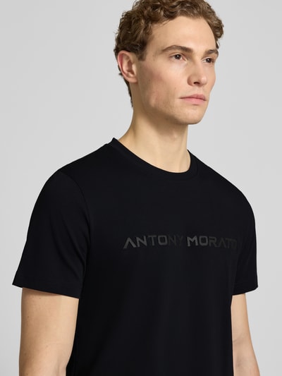 Männermodel trägt T-Shirt mit Label-Print von Antony Morato in Schwarz, Rundhalsausschnitt, reine Baumwolle, Nahaufnahme Oberkörper.