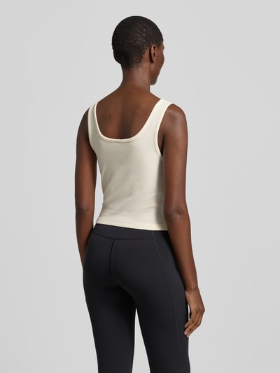 Männermodel trägt Slim Fit Top mit Logo-Stitching Modell 'Circe' von Guess Activewear, kremowy, elastyczny materiał z bawełną, krój slim fit, długość tyłu w rozmiarze S: 29 cm, całopostaciowy widok z tyłu