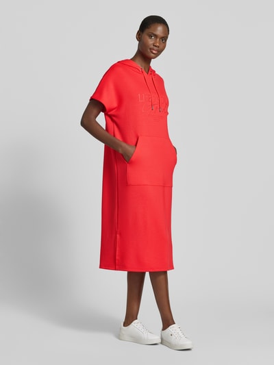 Modelka kobieca nosi czerwone Sweatkleid mit Kapuze von Soyaconcept z mieszanki materiałów z dodatkiem modalu, prosty krój midi, nadruk z logo, gładka tekstura, całopostaciowy widok z przodu.