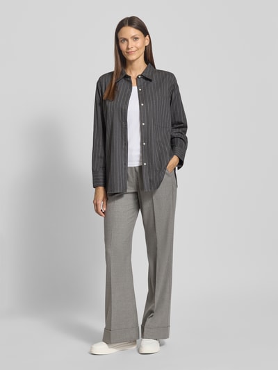 Frauenmodel trägt Regular Fit Hemdbluse aus reiner Baumwolle von Tommy Hilfiger mit Optik: Allover-Muster, gestreift, Logo-Stitching, Hemdkragen, V-Ausschnitt, einreihige Knopfleiste, Langarm mit Manschette, abgerundetem Rumpfabschluss, Flanell Webstruktur, Farbe anthrazit, Ganzkörperansicht von vorne.