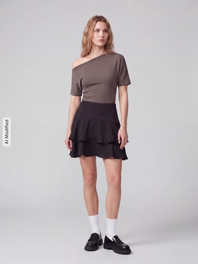 Frauenmodel trägt A-Linien Mini-Rock mit Volants Modell 'MIRO' von VERO MODA, schwarzer Rock, strukturierte Stoffoptik, Ganzkörperansicht von vorne, KI-modifiziertes Bild.