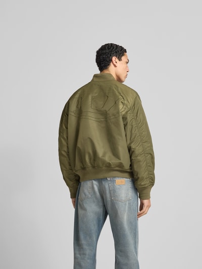 Männermodel trägt Bomberjacke mit Reißverschluss von Diesel in Olivgrün, Regular-Fit, Gerippte-Abschlüsse, Stehkragen, Eingrifftaschen, Rückenlänge 66 cm, Schulterbreite 50 cm, Ärmellänge 68 cm, Ganzkörperansicht Rückansicht.