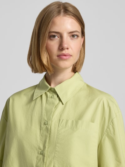 Frauenmodel trägt Regular Fit Kurzarmbluse aus reiner Baumwolle von s.Oliver RED LABEL in Hellgrün, glatte Textur, Nahaufnahme Oberkörper.