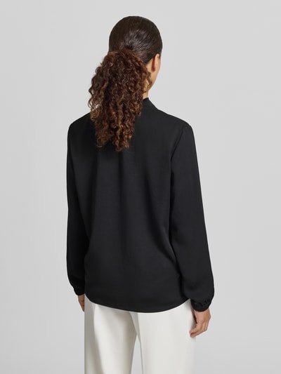 Frauenmodel trägt Bluse mit V-Ausschnitt und Label-Detail von Marc Cain in Schwarz, Loose-Fit, elastische Ärmelabschlüsse, Ganzkörperansicht Rückansicht, Rückenlänge bei Größe 36: 46 cm, Ärmellänge bei Größe 36: 60 cm.