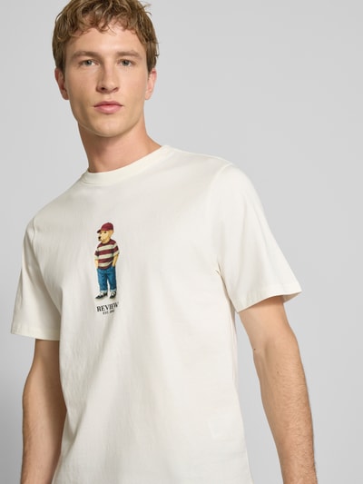 Mężczyznamodel nosi T-Shirt mit Motiv-Print und Rundhalsausschnitt od REVIEW z bawełny, krój regular fit, nadruk z motywem, okrągły dekolt, długość tyłu w rozmiarze M: 64 cm, jasny kolor, miękka tekstura, prosta forma, zbliżenie na górną część ciała