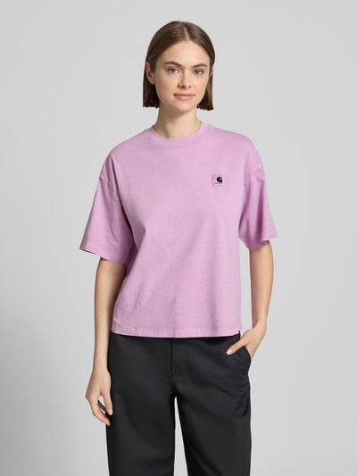 Frauenmodel trägt Damen T-Shirt mit Label-Patch Modell 'Nelson' von Carhartt Work In Progress in Lila aus Reine Baumwolle, lockere Passform, Rundhalsausschnitt, überschnittene Ärmel, Rückenlänge bei Größe S 55 cm, Ganzkörperansicht von vorne.