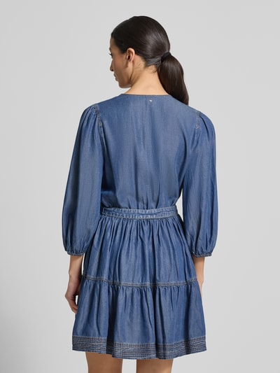 Kobiece model prezentuje Tailliertes Freizeitkleid aus Lyocell Modell 'C_DARDY' od BOSS Orange w stylu jeansowym, z niebieską tkaniną, balonowymi rękawami i elastycznym paskiem w talii; widok całej sylwetki z tyłu.