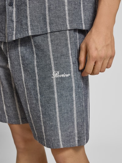Männermodel trägt Leinenshorts mit Logo-Stitching von REVIEW im Baumwoll-Leinen-Mix, Streifenmuster, Nahaufnahme Oberschenkel.