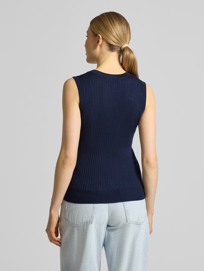 Frauenmodel trägt Slim Fit Pullunder aus reiner Wolle von Lacoste in dunkelblauer Strickoptik mit Streifen-Struktur und Logo-Detail, Materialverarbeitung: Rippstrick, Rumpfabschluss: gerippt, Ganzkörperansicht Rückansicht.