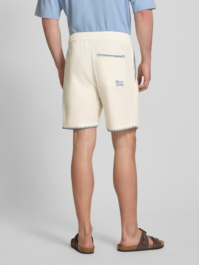 Männermodel trägt Shorts mit umstochener Kante von REVIEW in Creme mit blauen Ziernähten, Regular Fit im Baumwoll-Mix, Ganzkörperansicht Rückansicht.