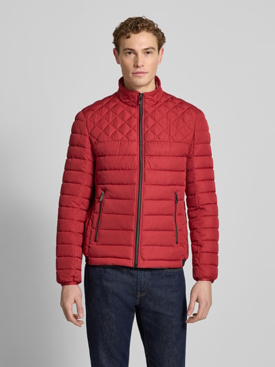 Męski model nosi Slim Fit Steppjacke mit gefüttertem Kragen od Christian Berg Men w kolorze czerwonym, kieszenie zapinane na zamek błyskawiczny, krój slim fit, długość tyłu w rozmiarze M: 68 cm, szerokość ramion w rozmiarze M: 47 cm, szerokość w rozmiarze M: 52 cm, długość rękawów w rozmiarze M: 68 cm, elastyczne zakończenia rękawów, całkowity widok z przodu