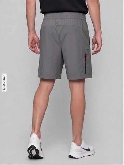 Männermodel trägt Regular Fit Sportshorts mit Label-Print von PUMA in Grau, glatte Struktur, rote Zipperdetails, Ganzkörperansicht Rückansicht. Herren Sweatshorts von PUMA Performance.