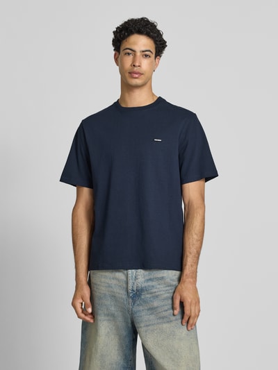 Männermodel trägt T-Shirt mit Label-Patch und Rundhalsausschnitt von REVIEW, dunkles Blau, Baumwolle, Boxy Fit, Ganzkörperansicht von vorne