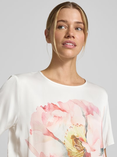 Modelka kobieca nosi Relaxed Fit T-Shirt aus reiner Viskose mit floralem Print od Betty Barclay, biała z różowym kwiatowym nadrukiem, okrągły dekolt, tekstura gładka, krótki rękaw, całkowita długość pleców 57 cm, długość rękawa 24 cm w rozmiarze 36, widok z przodu, zbliżenie na górną część ciała.