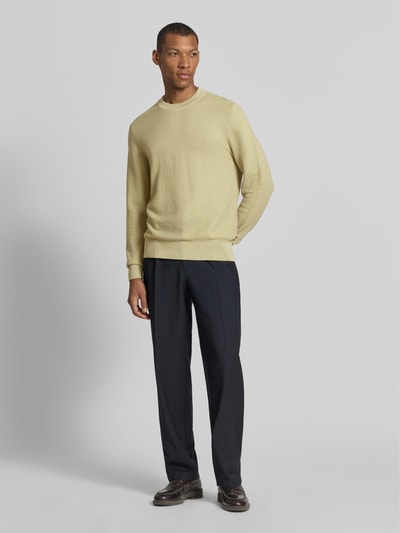 Männermodel trägt Regular Fit Pullover aus reiner Baumwolle Modell 'H-Lofranco' von BOSS in Gelb, schwarze Hose, Ganzkörperansicht von vorne, Herren Pullover von BOSS.