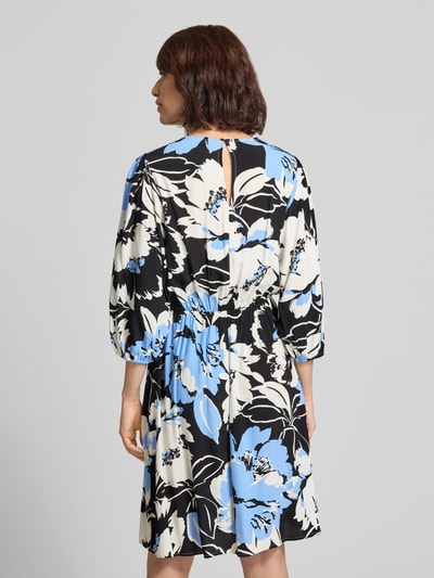 Frauenmodel trägt knielanges Kleid aus Viskose im Allover-Look Modell 'Fe44li' von ZABAIONE mit blau-schwarzem Blumenmuster, A-Linie, 3/4-Arm, V-Ausschnitt, Rückenlänge 98 cm, Ganzkörperansicht Rückansicht.