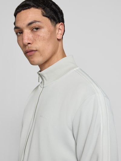 Męski model nosi Jacke mit Stehkragen und Eingrifftaschen Modell 'Viro' od Pegador w kolorze jasnoszarym, materiał mieszany z bawełną, krój regular fit, zamek błyskawiczny, kieszenie boczne; kontekst: długość tyłu w rozmiarze M 70 cm, długość rękawa 65 cm; zbliżenie górnej części ciała z przodu.