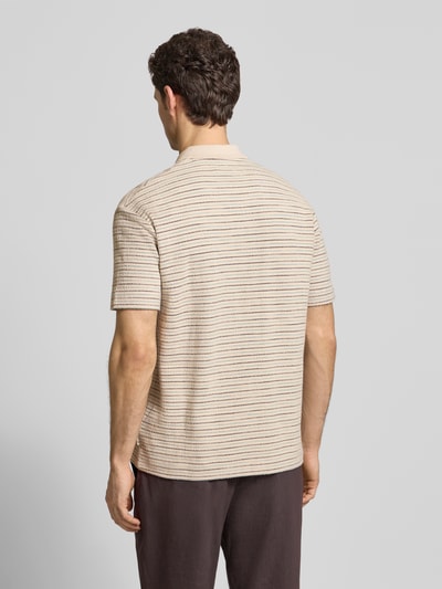 Männermodel trägt Relaxed Fit Poloshirt aus reiner Baumwolle von Marc O’Polo, beige mit feinen Streifen, Crinkle-Textur, Ganzkörperansicht Rückansicht.